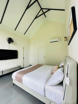 Habitación de hotel con cama, televisor de pantalla plana, equipo de aire acondicionado y ventilador de techo.
