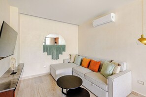 Een moderne woonkamer met een bank, een rond bijzettafeltje en een televisie.