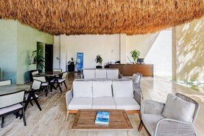 Eine moderne Lobby mit einer Rezeption, einer Sitzecke und einer großen Strohdeckung.