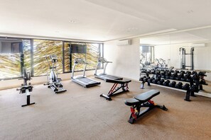 Een fitnessruimte met loopbanden, krachtapparaten en gewichten.