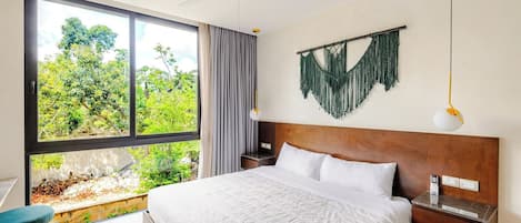 A modern hotel room with a large window, a bed with white linens, a wooden headboard, and a wall-mounted macrame piece.