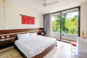 Een moderne slaapkamer met een groot bed, een nachtkastje, een bureau en uitzicht op groen door het raam.