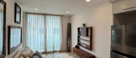 A modern living room with a sofa, a coffee table, a TV, and a refrigerator.