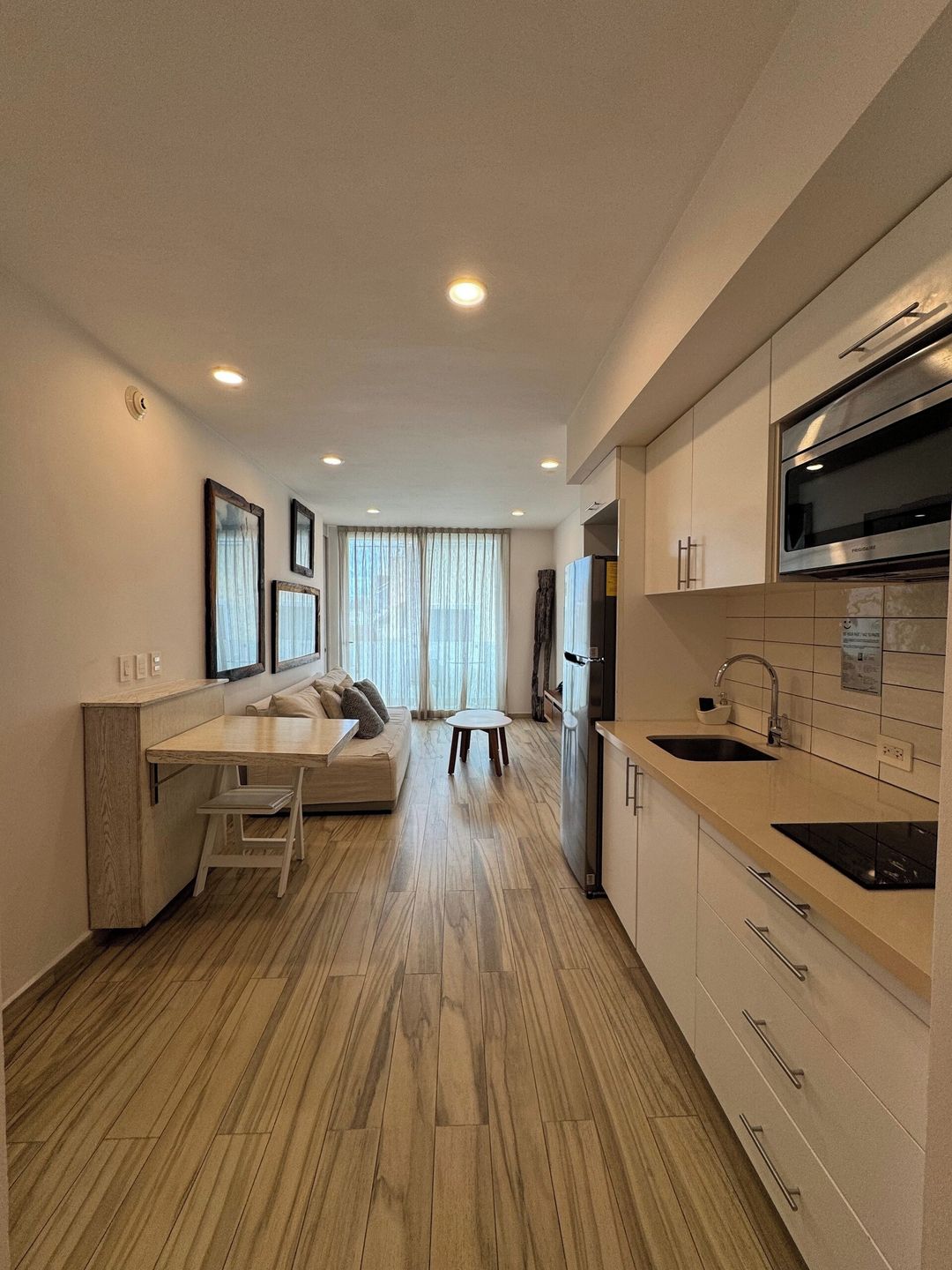 A modern kitchen with a dining area, wooden flooring, and built-in appliances.