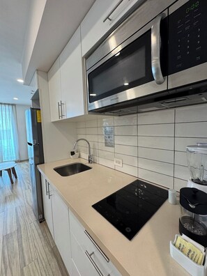 A modern kitchen with a built-in microwave, a sink, and a countertop with a blender. - King 1BR · 1.5 Baths · Rooftop Pool · 5th Ave (Playa del Carmen)