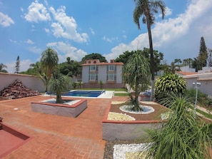 Ein Wohnhaus mit Schwimmbad, Terrasse und einem zweistöckigen Haus mit Ziegeldach.