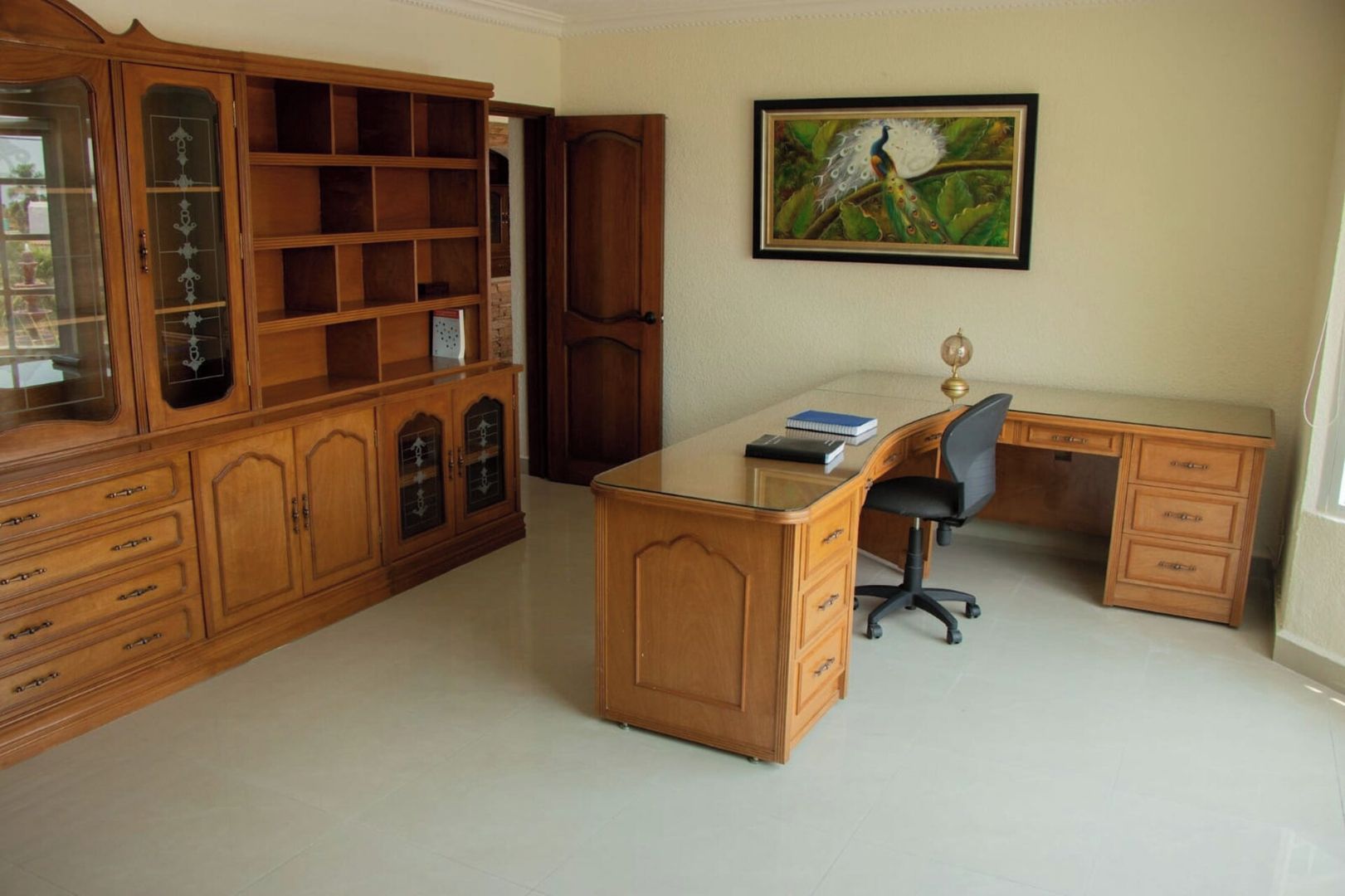 Une pièce comprenant un bureau en bois, une chaise, une bibliothèque et un tableau encadré accroché au mur.