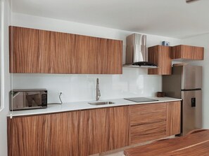 A modern kitchen with wooden cabinets, a stainless steel refrigerator, and a built-in microwave. - Aldea Zama · 2BR with pool · Guest favorite (Tulum)