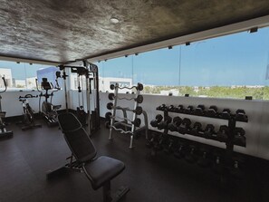 A gym with exercise equipment, a bench, and dumbbells. - Aldea Zama · 2BR with pool · Guest favorite (Tulum)