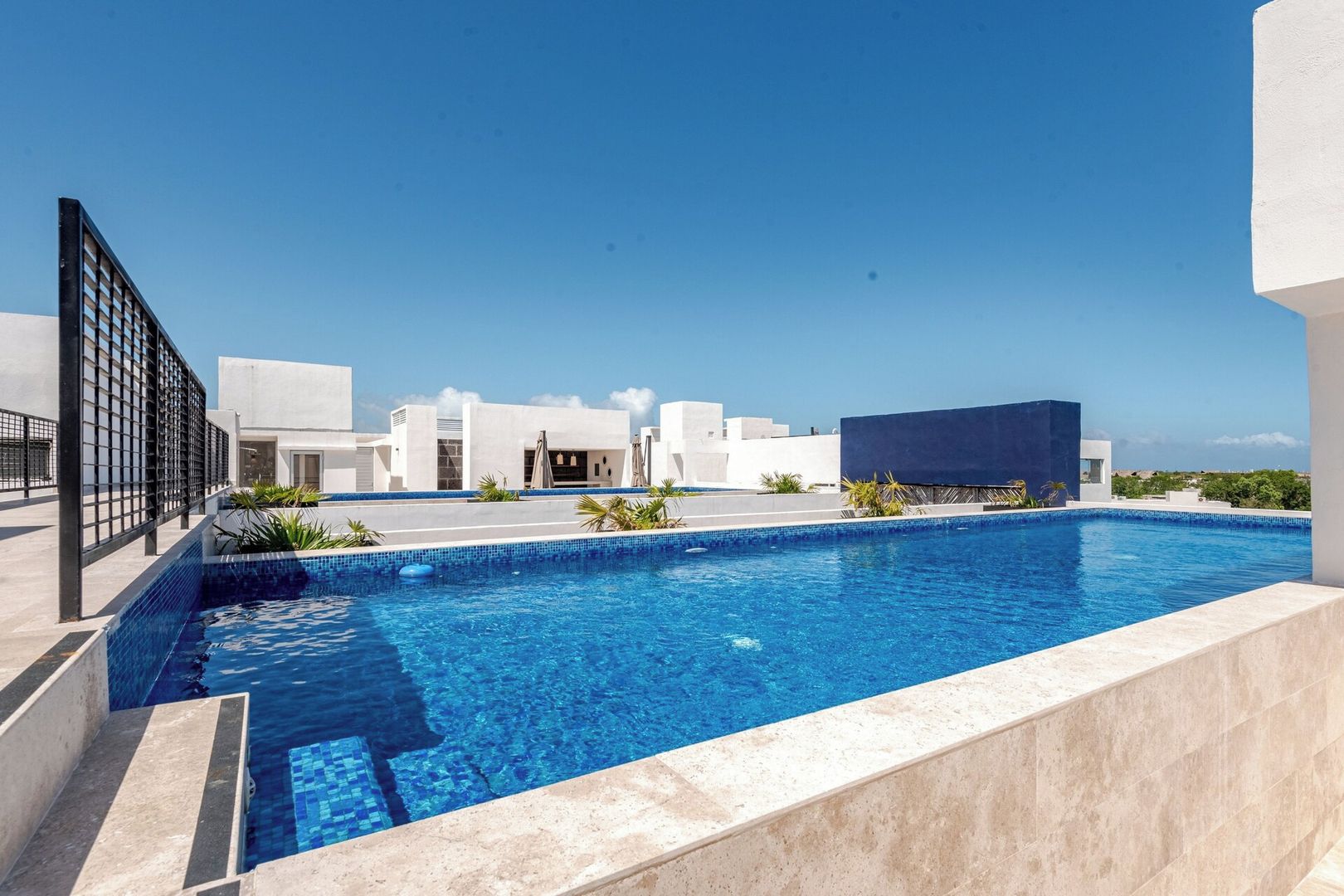 A swimming pool with a clear blue water, surrounded by a white building with a modern design.