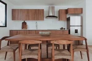 A modern kitchen with wooden cabinetry, a large island with a bowl, and a built-in stove. - Aldea Zama · 2BR with pool · Guest favorite (Tulum)