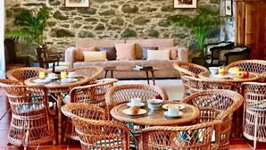 Ein gemütlicher Lounge-Bereich mit Korbmöbeln, einer Steinwand und einer Couch.