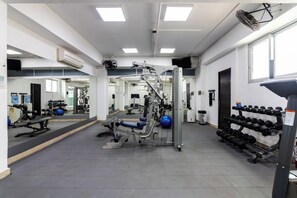 Ein Fitnessraum mit Trainingsgeräten, einem Spiegel und einer Hantelbank.