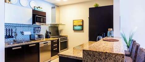 A modern kitchen with granite countertops, stainless steel appliances, and a backsplash with a blue and white pattern.