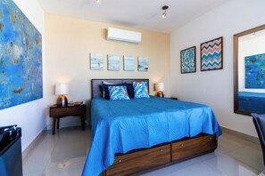 Ein Hotelzimmer mit Bett, Nachttischen, Wandbildern und einer Klimaanlage.