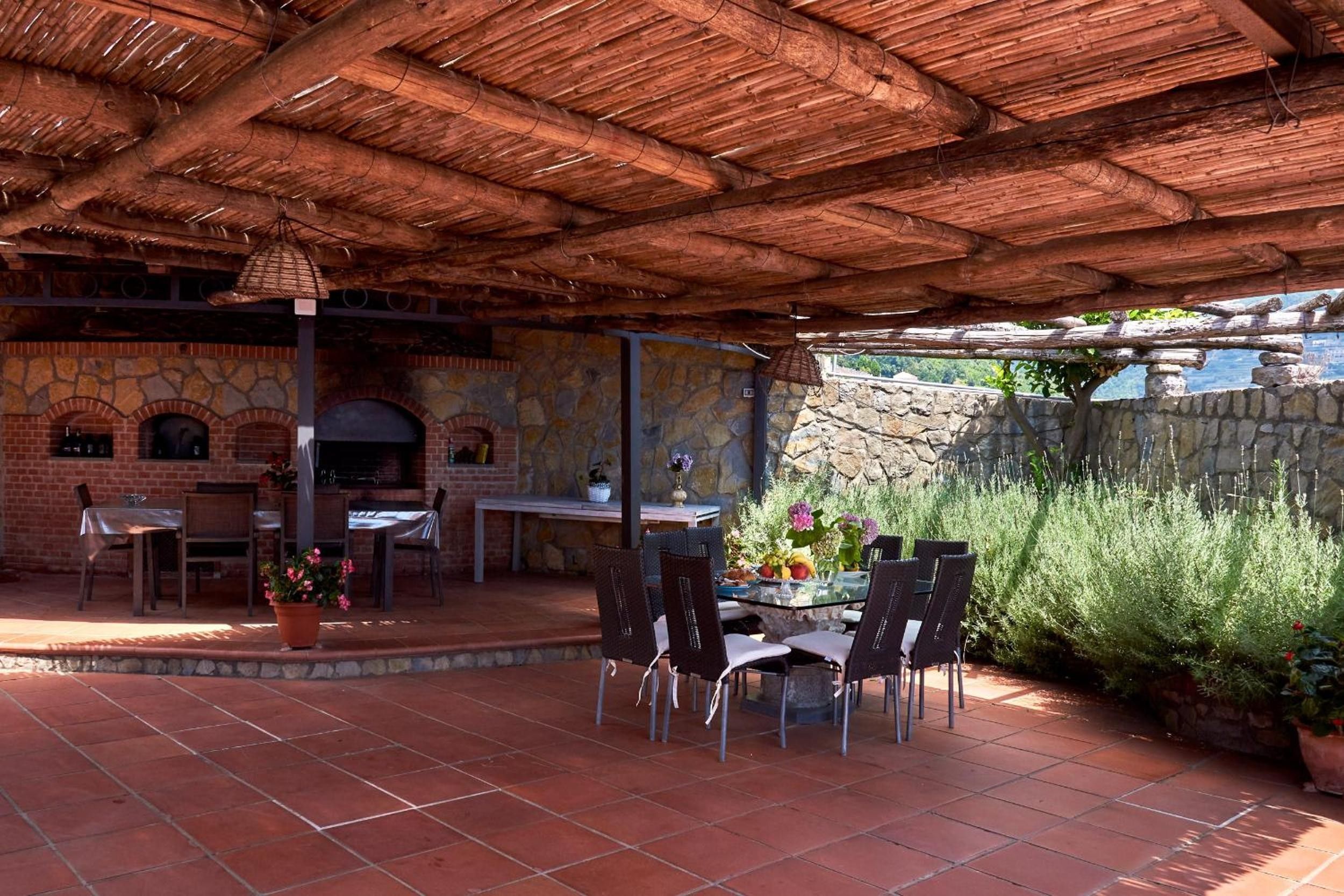 Une terrasse extérieure dotée d’une cheminée en briques, de murs en pierre et d’un toit de chaume.