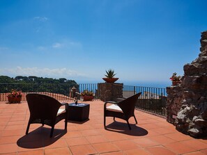 A terrace with two wicker chairs, a table, and potted plants.