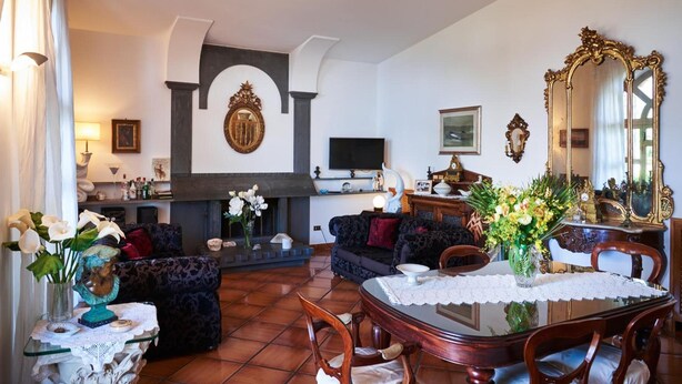 Sala de estar com lareira, televisão e área de jantar com mesa e cadeiras.