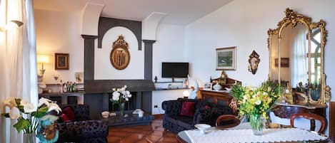 A living room with a fireplace, a television, and a dining area with a table and chairs.