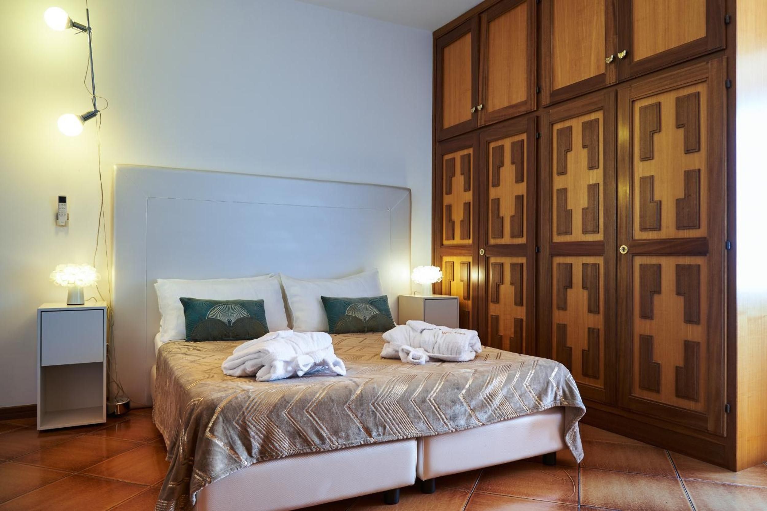 A hotel room with a bed, bedside lamps, a wardrobe, and a nightstand.