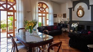Uma sala de estar ampla com área de jantar, janelas grandes e lareira.