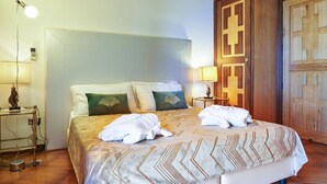 Quarto de hotel com cama, duas luminárias de cabeceira, mesa de cabeceira e guarda-roupa de madeira.