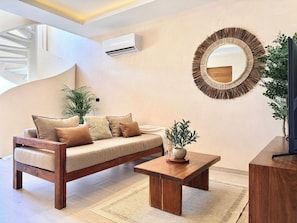 A modern living room with a sofa, coffee table, and a round mirror on the wall. - Please note: electricity is not included in reservations longer than 28... (Tulum)