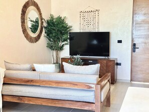 A living room with a sofa, a television, a decorative wall hanging, and a potted plant. - Please note: electricity is not included in reservations longer than 28... (Tulum)