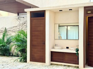 A bathroom with a wooden door, a sink, and a mirror. - Please note: electricity is not included in reservations longer than 28... (Tulum)