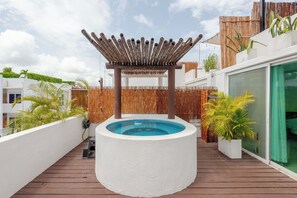 Ein Pool auf dem Dach mit einer Holzpergola, umgeben von weißen Wänden und einem Holzdeck.