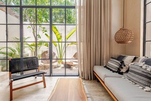 Ein Zimmer mit großem Fenster, einer Couch, einer Bank und einer Hängeleuchte.