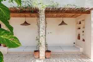 A covered seating area with a stone pillar, potted plants, and hanging light fixtures. - Townhouse with private pool facing the jungle (Tulum)