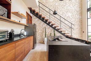 Eine moderne Küche mit Steinwand, Holzschränken, integriertem Backofen und einer schwarzen Arbeitsplatte.