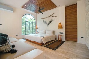 A modern bedroom with a large bed, a ceiling fan, a wall-mounted light fixture, and a large window. - Townhouse with private pool facing the jungle (Tulum)
