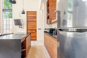 Eine moderne Küche mit Edelstahlkühlschrank, Holzschränken und einem großen Fenster für natürliches Licht.