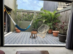 Eine Terrasse mit einer Hängematte, zwei Stühlen und Blumentöpfen.