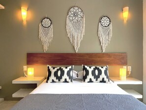 A hotel room with a wooden headboard, a bed with patterned pillows, and wall-mounted macrame dreamcatchers. - Sweet Apartment Tulum town and Great Pool (Tulum)