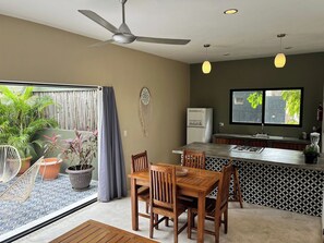 A modern kitchen with a built-in island, a ceiling fan, and a large window overlooking greenery. - Sweet Apartment Tulum town and Great Pool (Tulum)