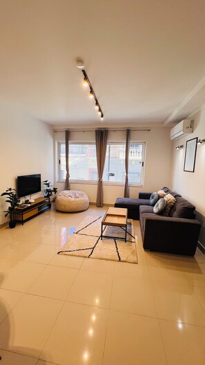 A modern living room with a flat-screen TV, a sofa, a coffee table, and a bean bag. - St. Julian's Central Apartment 1 (St. Julian's)