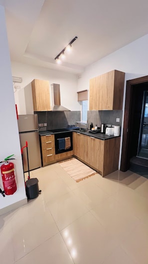 A modern kitchen with wooden cabinets, stainless steel appliances, and a tiled floor. - St. Julian's Central Apartment 1 (St. Julian's)