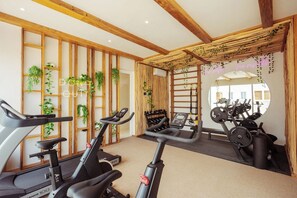 A gym with exercise equipment, wooden beams, and plants. - NUEVO Apartamento en La Veleta (Tulum)