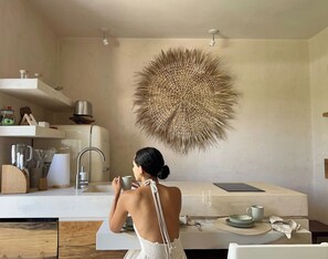 A modern kitchen with a central island, a large decorative wall piece, and a person taking a photo. - NUEVO Apartamento en La Veleta (Tulum)