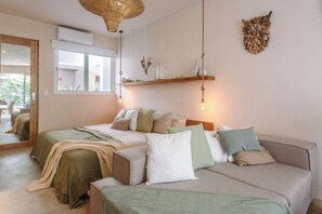 A bedroom with a bed, a sofa, a mirror, and a hanging light fixture. - NUEVO Apartamento en La Veleta (Tulum)