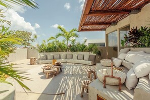 An outdoor living area with a curved sofa, round tables, and a pergola. - NUEVO Apartamento en La Veleta (Tulum)