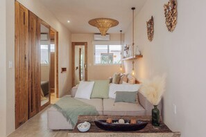 A cozy living room with a sofa, pillows, a bowl of snacks, a vase, and a hanging light fixture. - NUEVO Apartamento en La Veleta (Tulum)