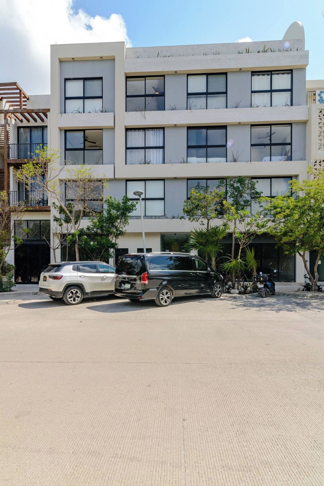 A multi-story building with a flat facade, large windows, and a paved ground area.