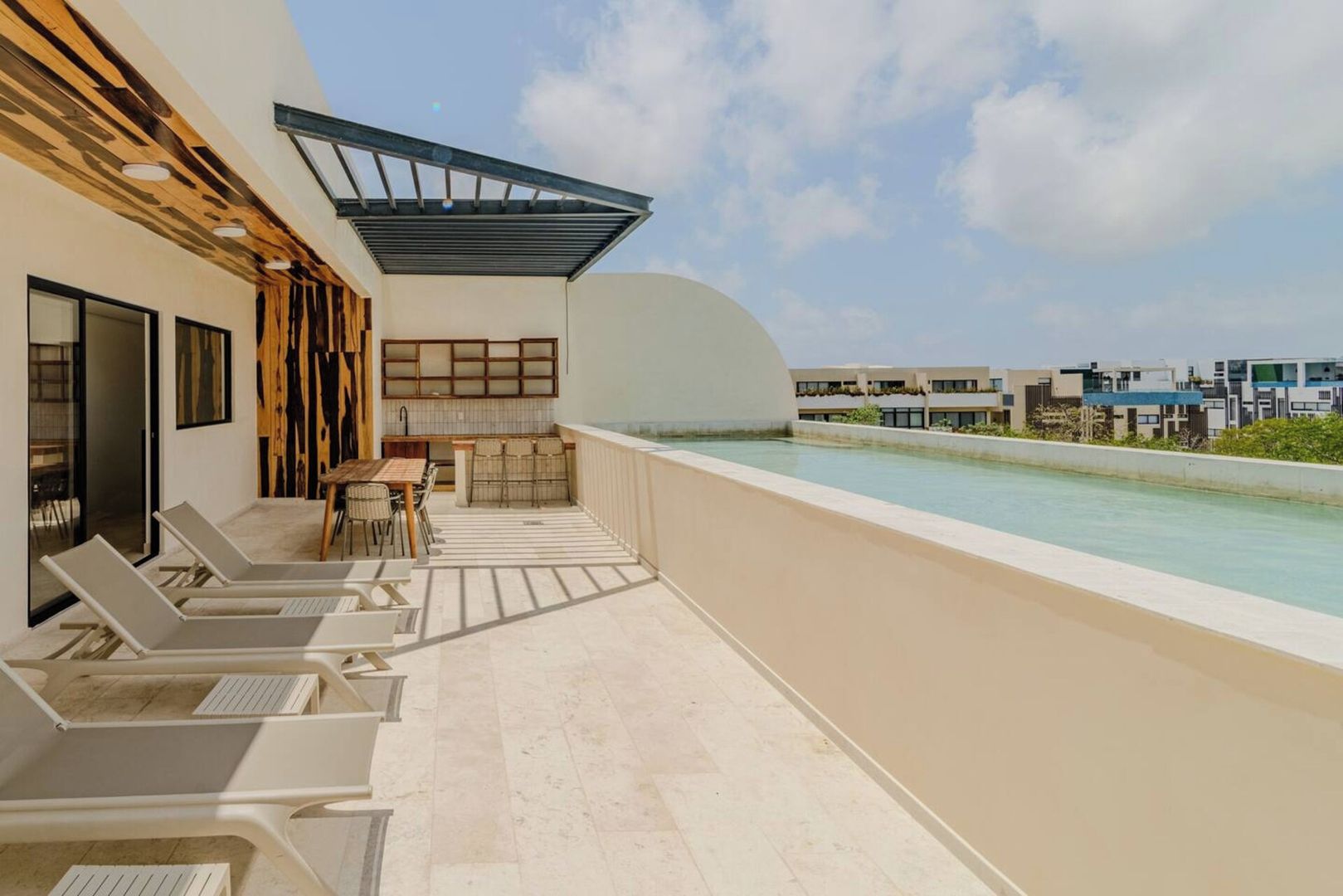 A rooftop terrace with a pool, lounge chairs, and a dining area.