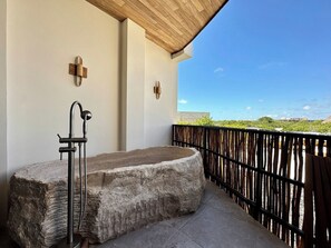A stone bathtub on a balcony with a view of a distant landscape. - Relaxing Lakeside Retreat Pool Hot Tub and Patio (Tulum)