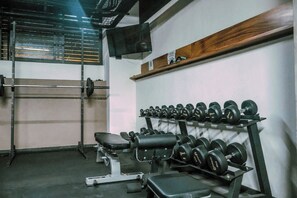 A gym with weightlifting equipment, a bench, and a television on the wall. - Relaxing Lakeside Retreat Pool Hot Tub and Patio (Tulum)