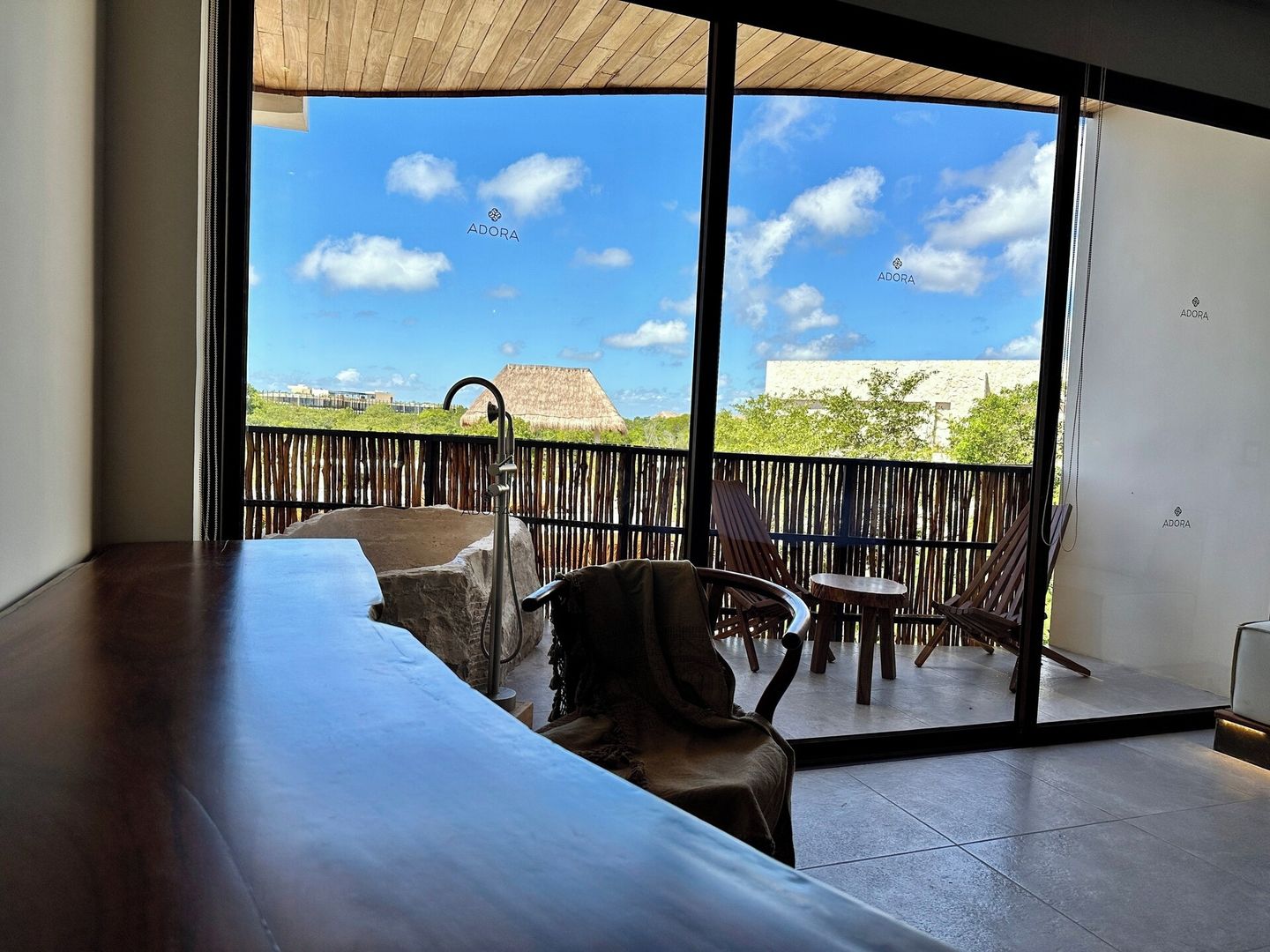 Een modern balkon met een houten plafond, een stenen tafel en een stoel.